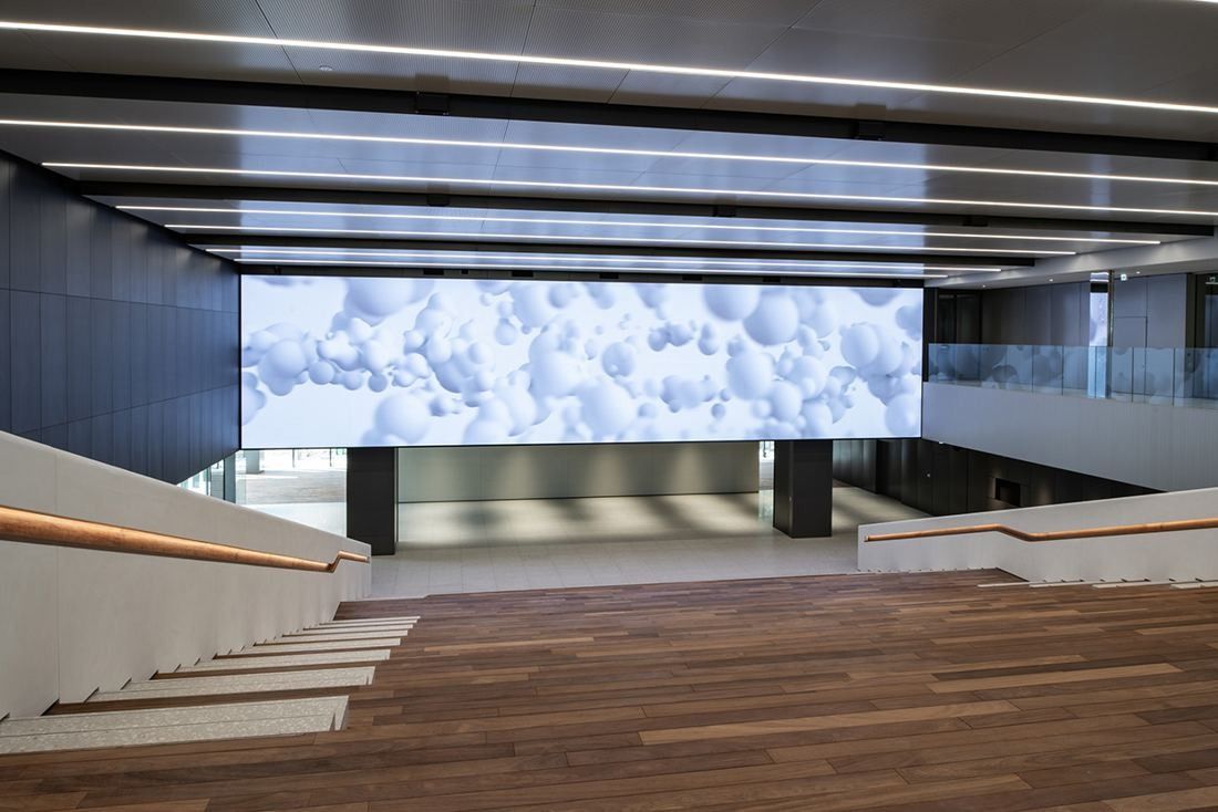 Nikon: Atrium seen from the top of wooden steps toward a lit screen