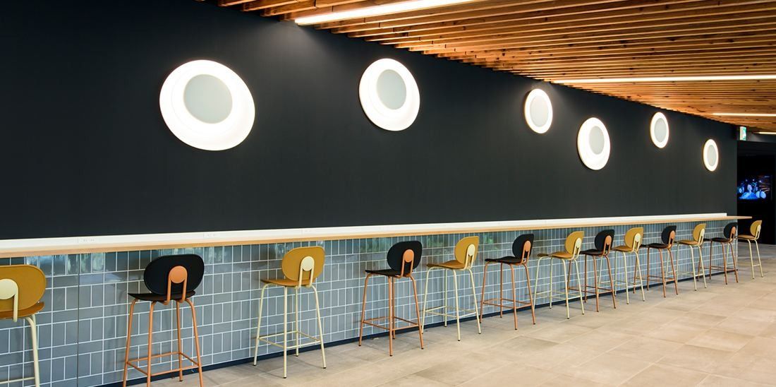 Nikon: Counter seating with stools below round lights on a dark wall