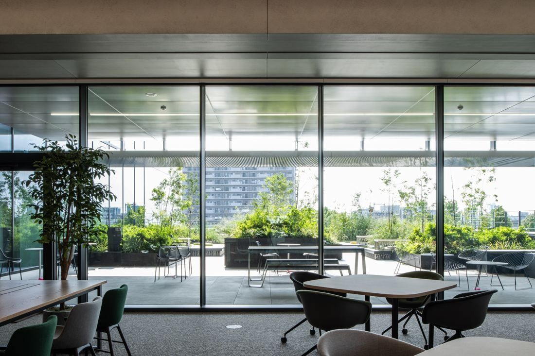 Nikon: Dining area with tables behind a glass wall opening onto greenery