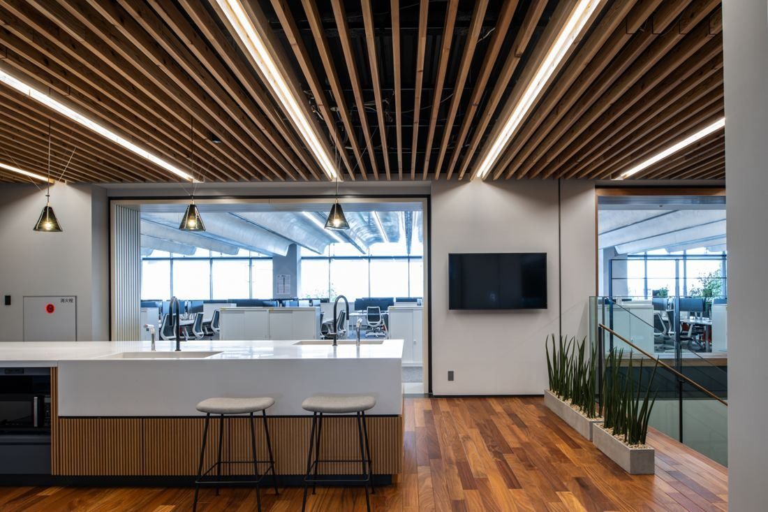 Nikon: Kitchen counter with stools under a wooden slatted ceiling, offices beyond glass