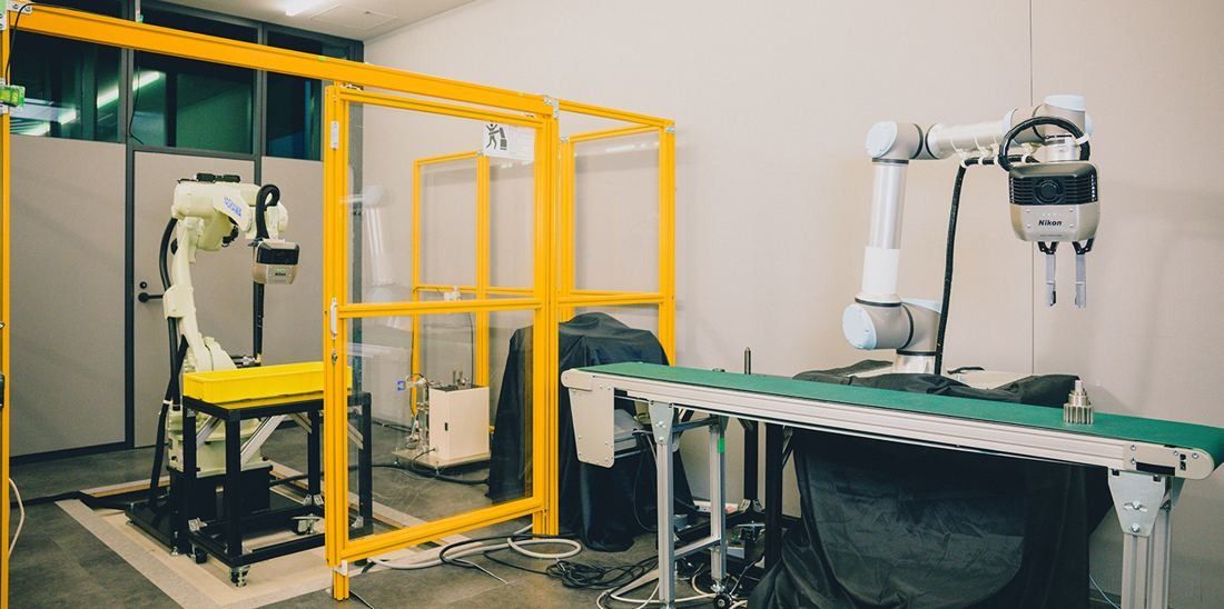 Nikon: Lab space with yellow frames, robot arms and a conveyor