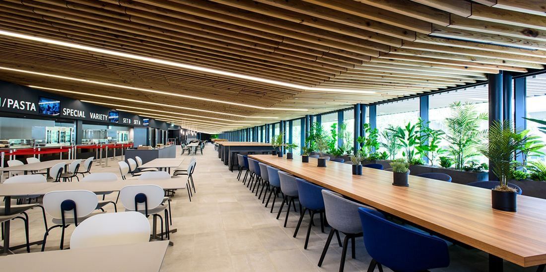 Nikon: Long communal tables in a dining hall with a slatted wooden ceiling