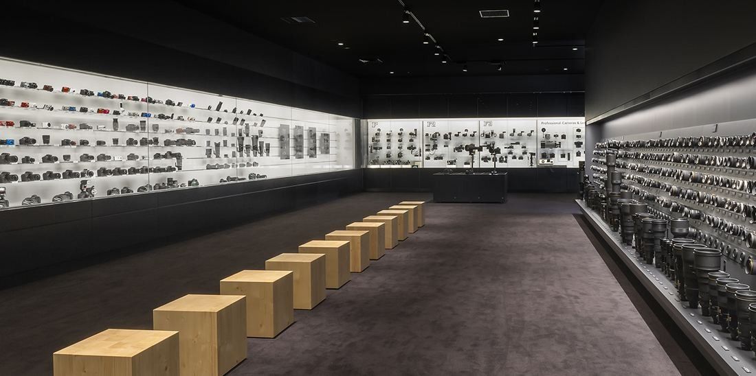 Nikon: Long gallery with illuminated wall cases and wooden stools