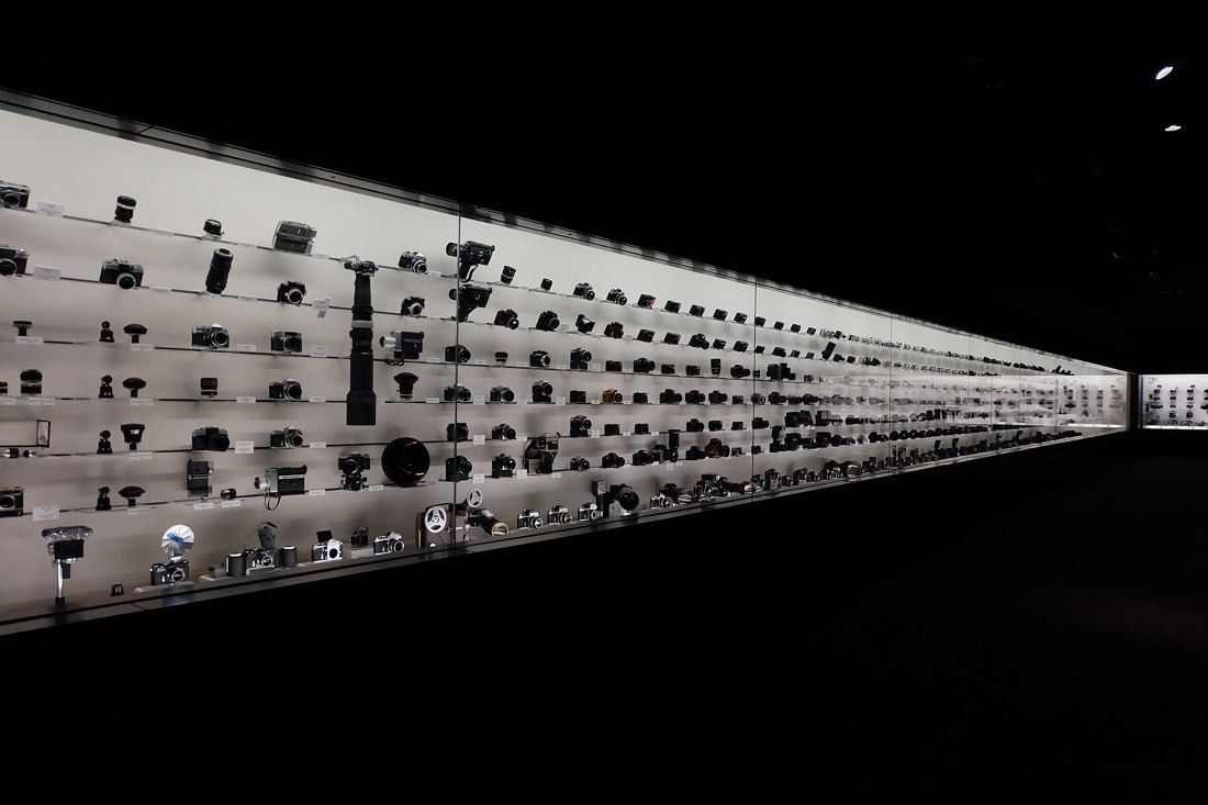 Nikon: Long illuminated wall of cameras in a dark room