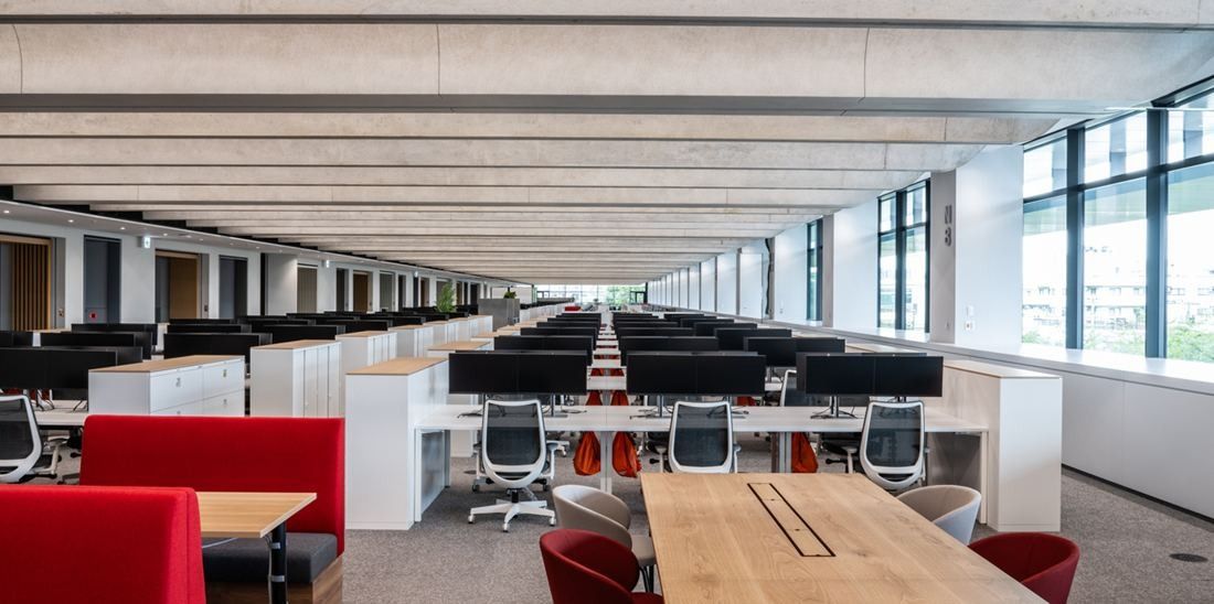 Nikon: Long office floor with desks, red booth seating and a central table