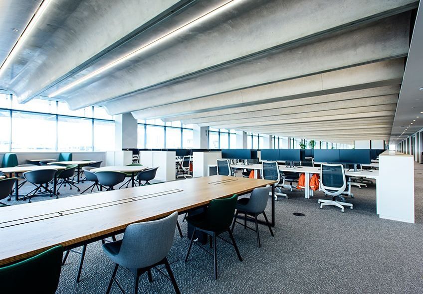 Nikon: Office floor with long tables and chairs under a ribbed ceiling
