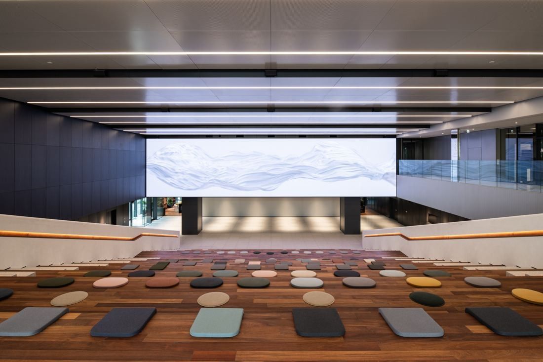 Nikon: Tall atrium with wide wooden steps facing a large wall screen
