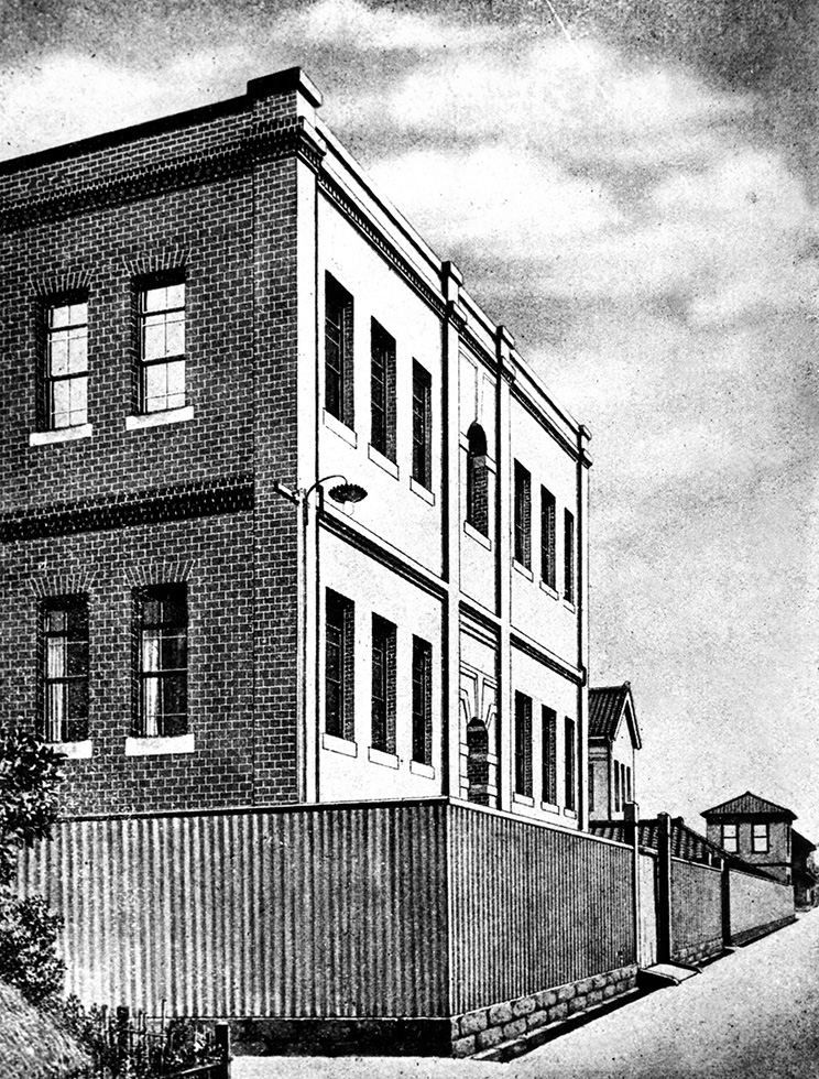 Two-storey brick building behind a wooden fence on a street corner
