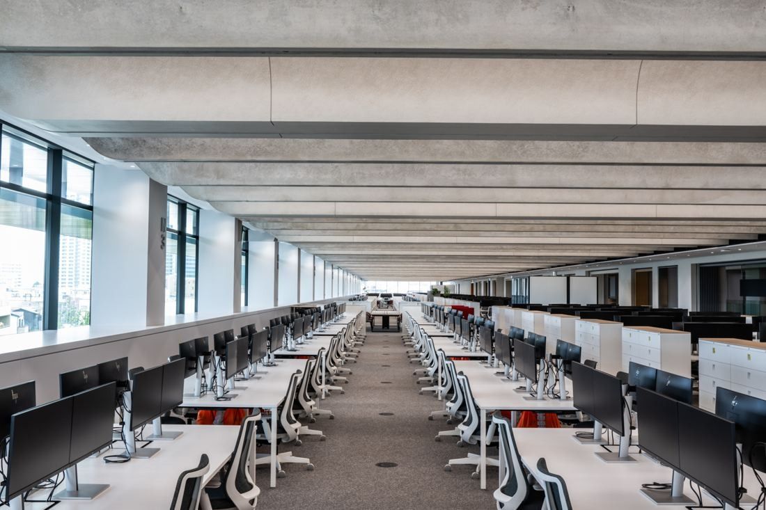 Nikon: Very long open-plan office floor with rows of desks and monitors