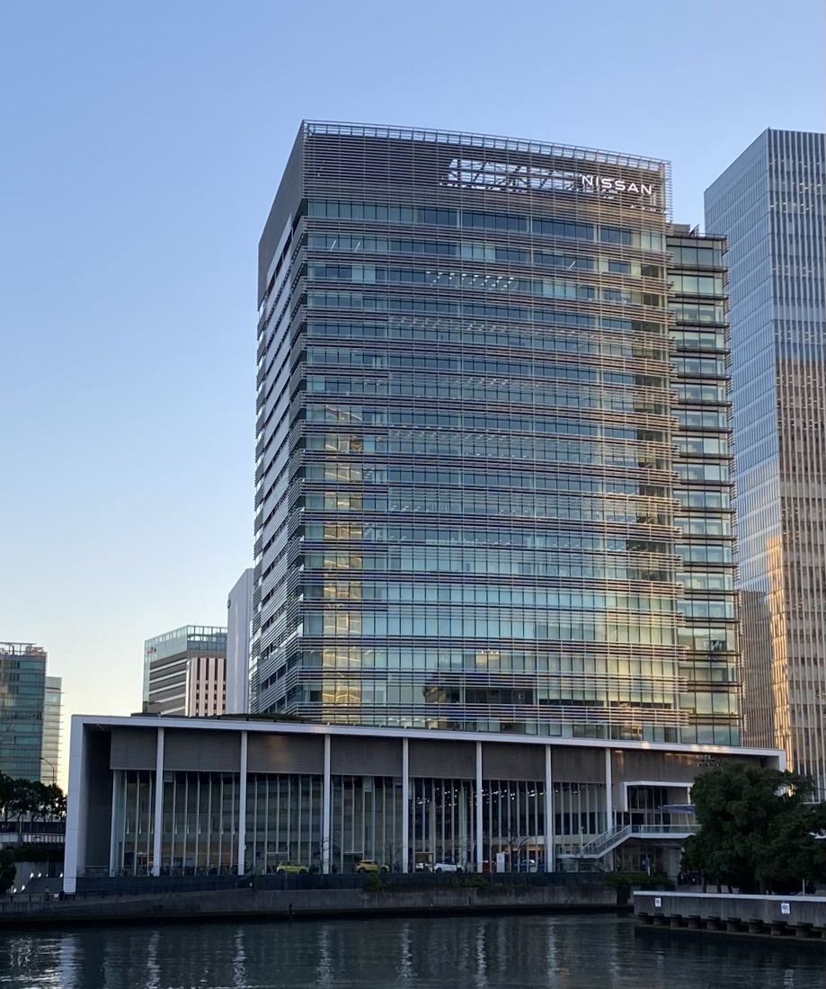 Nissan: Glass tower catching warm light, with its podium by the water