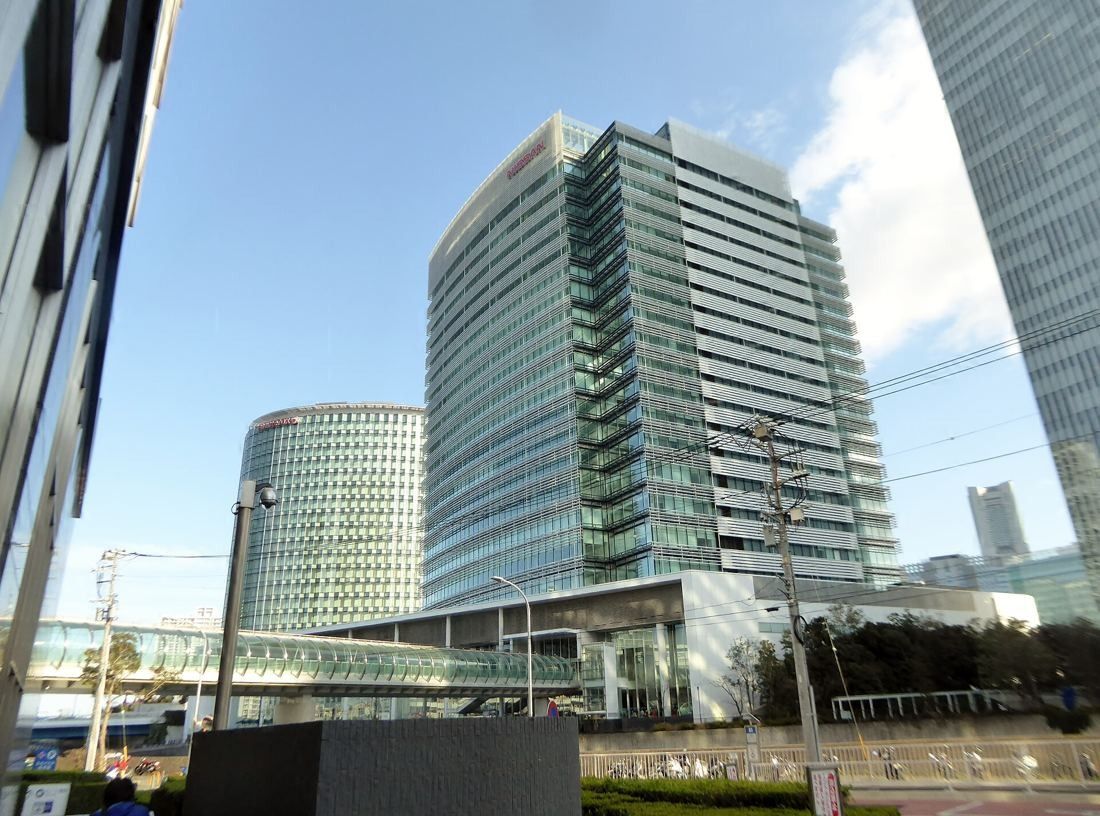 Nissan: Glass tower rising above a pedestrian bridge, next to a round glass building