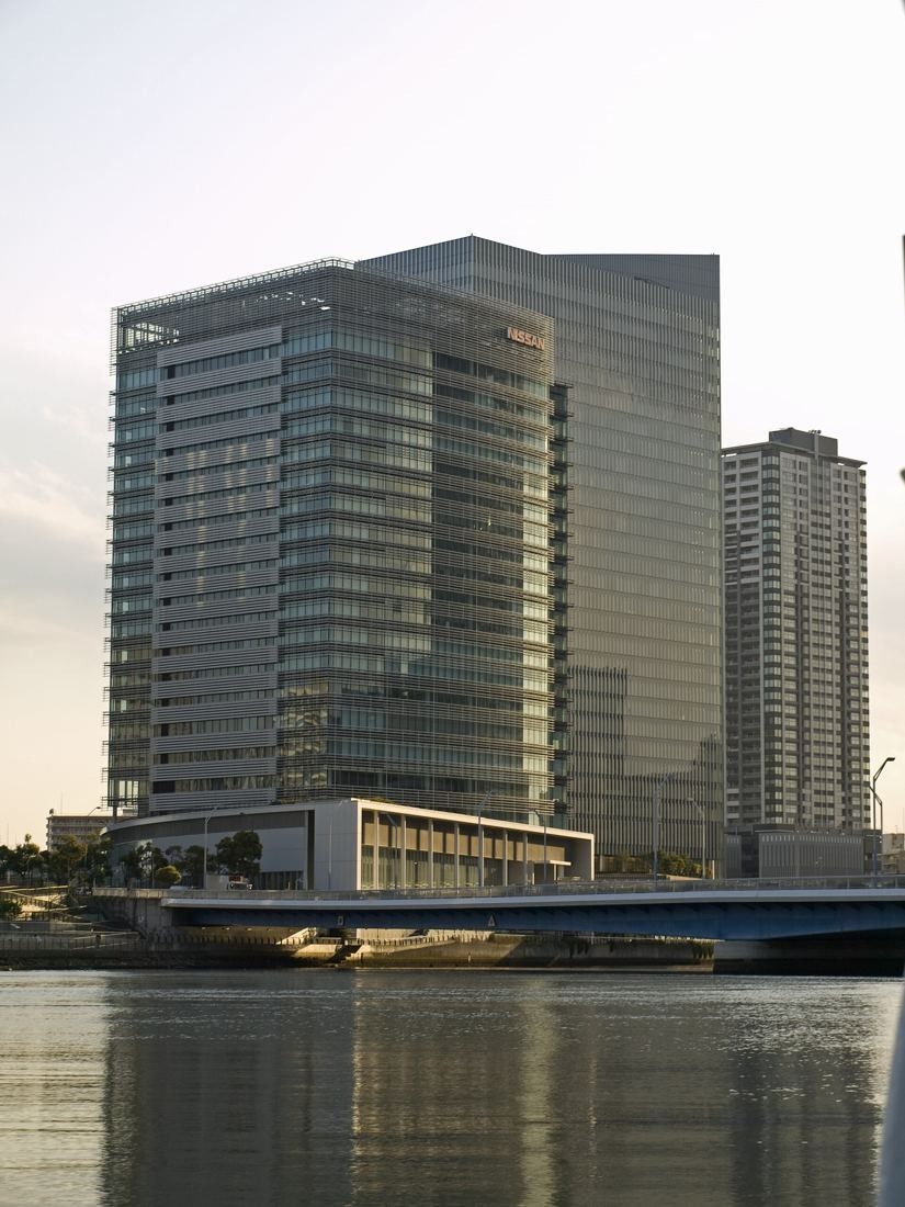 Nissan: Glass tower seen from water level with a bridge in front