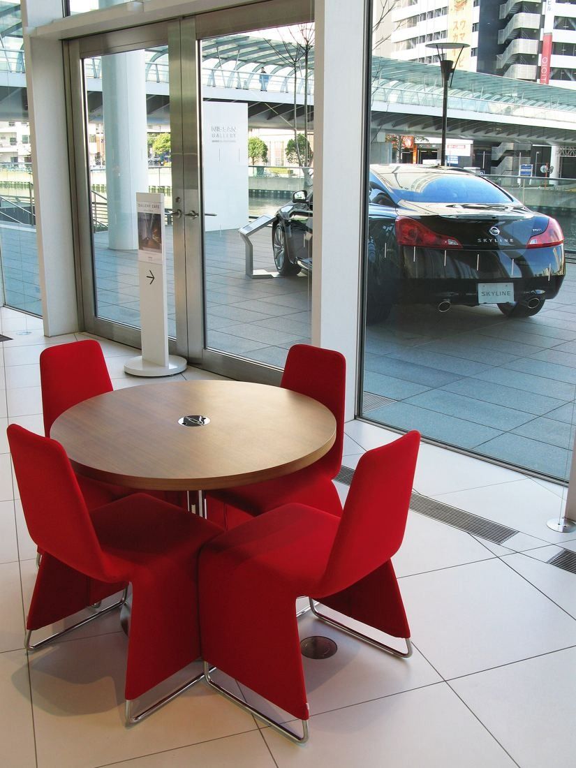 Nissan: Round table with red chairs beside a glass wall