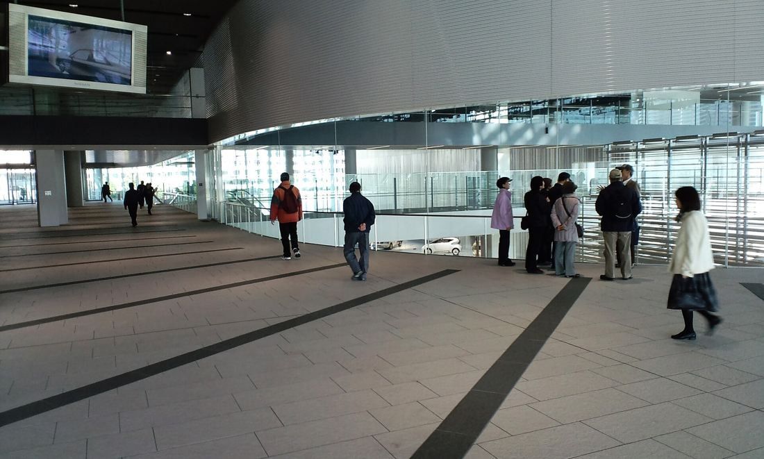 Nissan: Visitors on a wide stone deck looking down through glass rails into a hall below