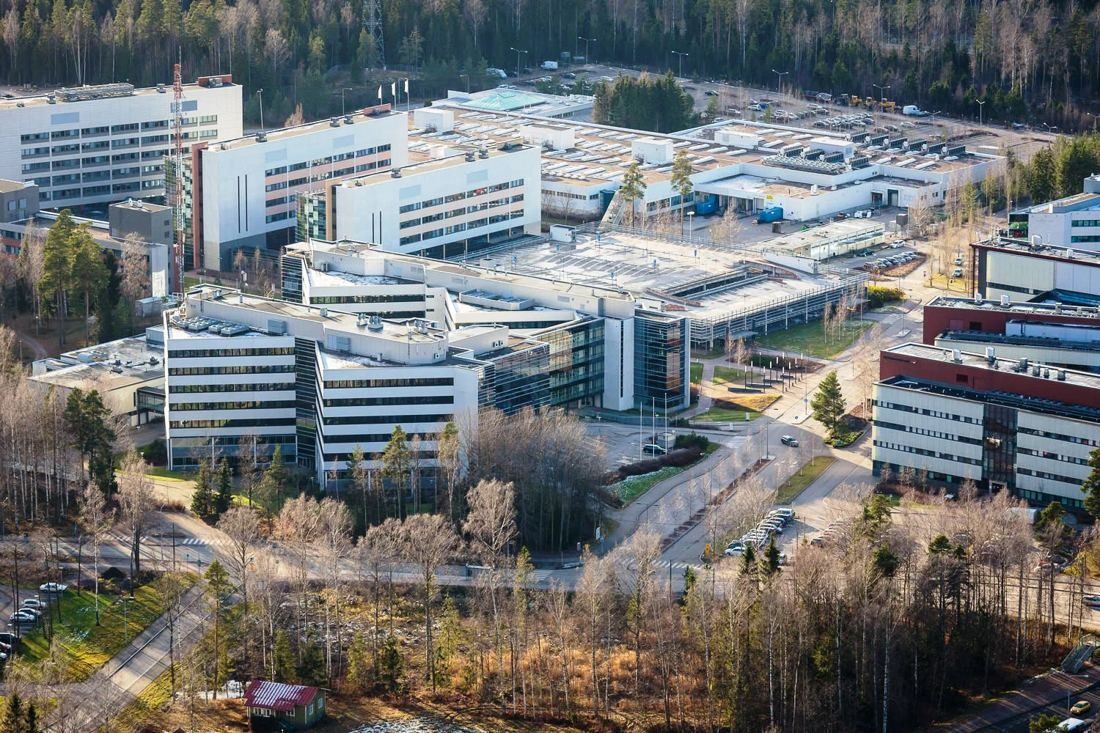 Aerial view of a large campus of white and glass office buildings surrounded by forest