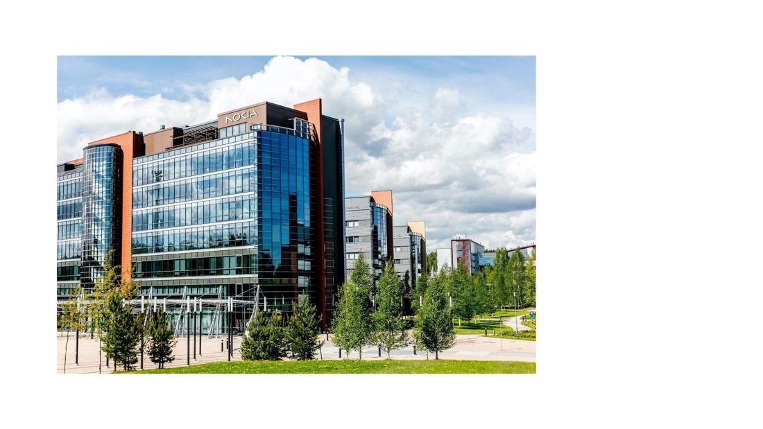Nokia: Glass and copper-coloured office building with the Nokia sign, young trees and a lawn in front