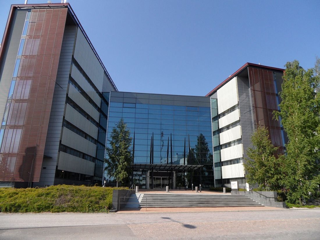 Nokia: Glass entrance hall between two office wings with brown façades, trees and a lawn in front