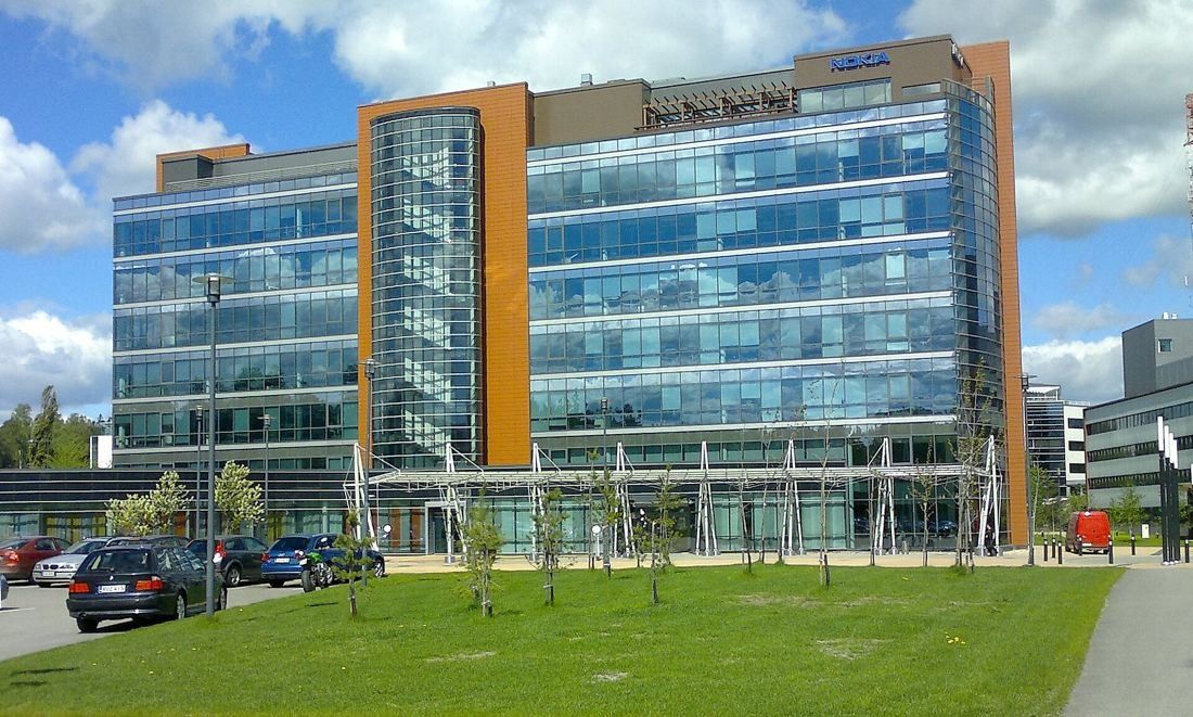 Nokia: Glass office building with orange vertical panels behind a lawn and parked cars