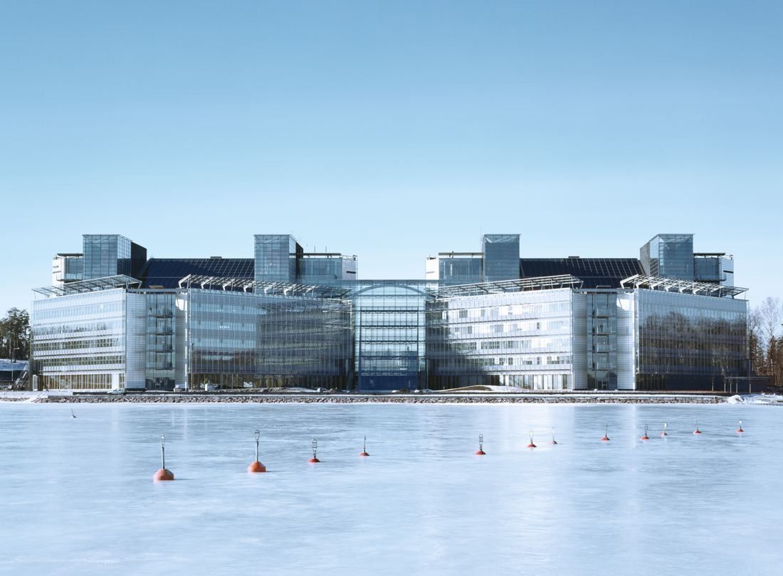 Glass office complex of several blocks seen across a frozen bay under a blue sky