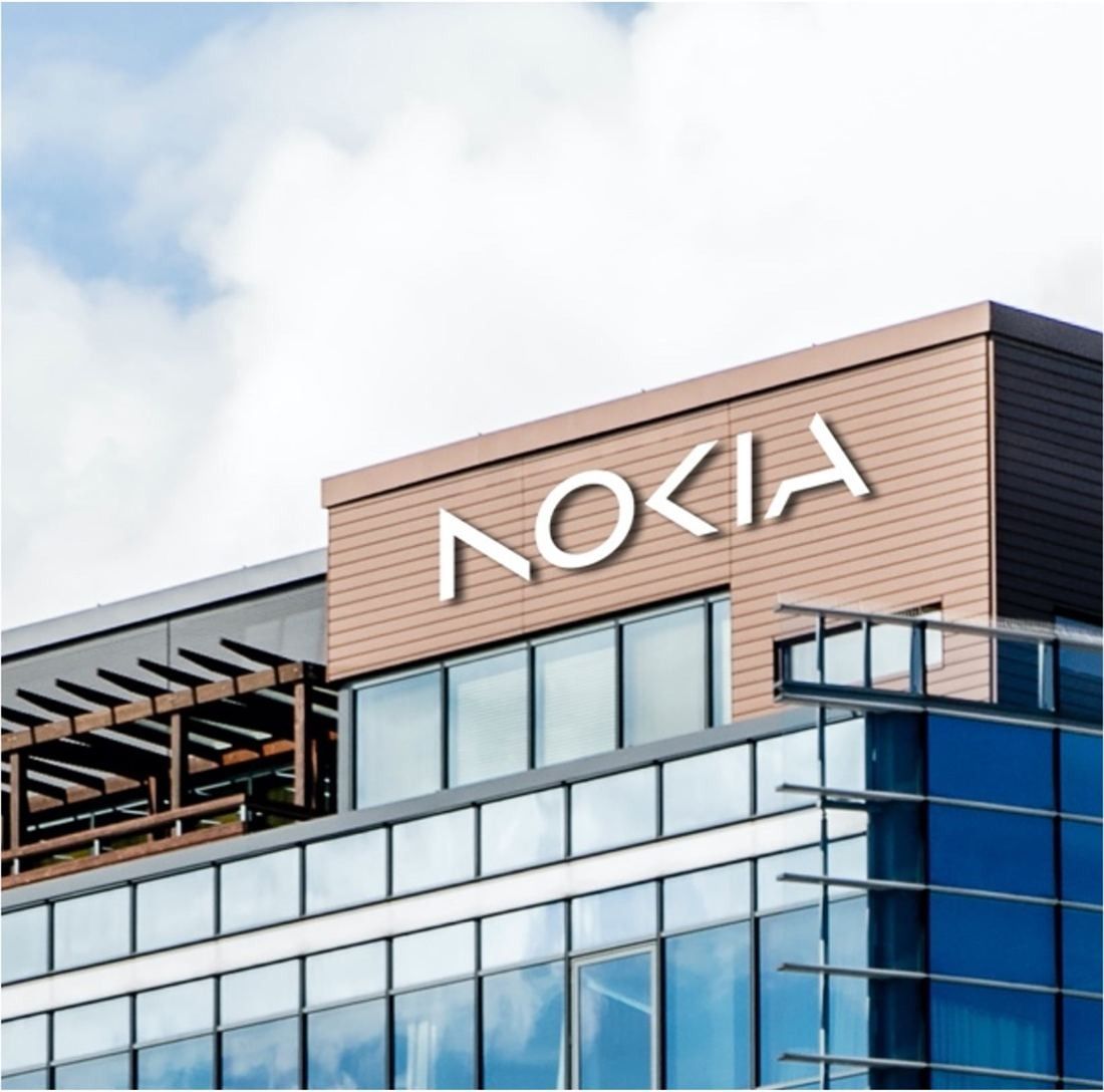 Nokia: Upper floors of a glass office building with a large Nokia sign on a brown façade against a pale sky
