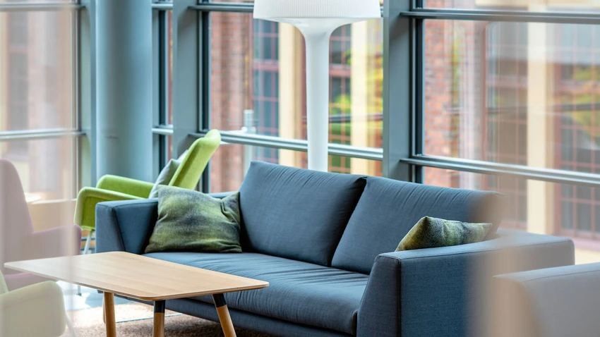 Nordea: Blue sofa and wooden coffee table by large windows