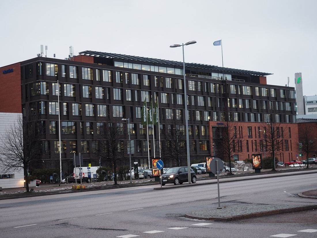 Dark-facaded office buildings with red-brick lower parts along a wide street