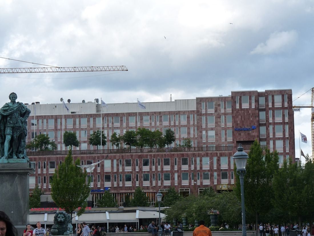 Large red-brick office block seen across Kungsträdgården with a statue in front