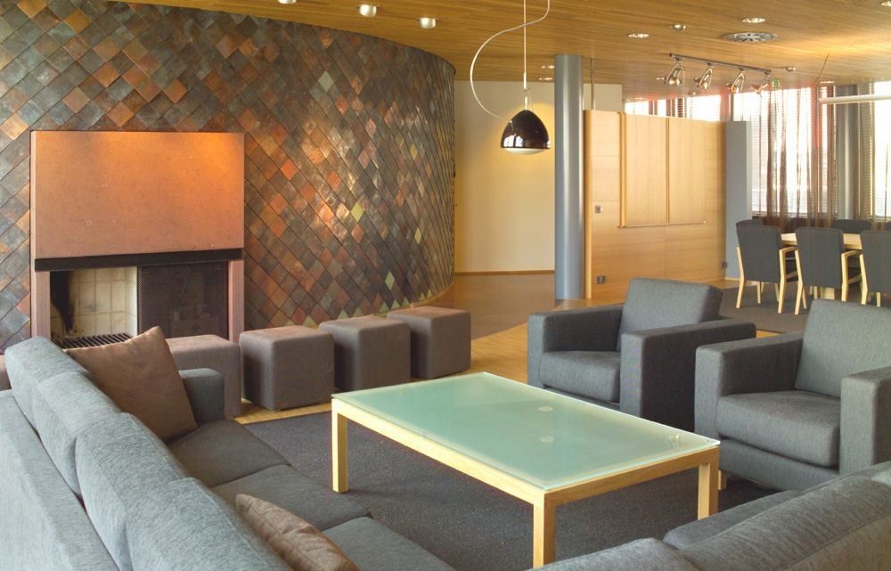 Nordea: Lounge with grey armchairs, a fireplace and a dark tiled wall
