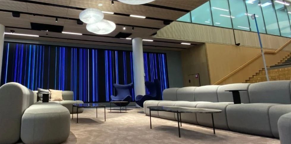 Nordea: Lounge with grey sofas in front of a wall of blue vertical lights