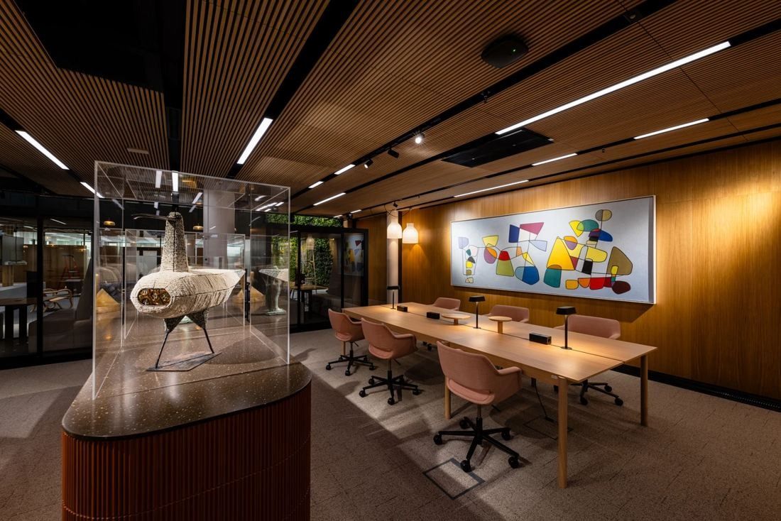 Nordea: Meeting table with pink chairs beside a colourful artwork and a sculpture in a glass case