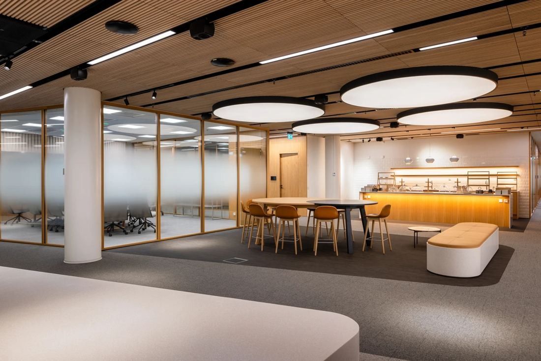 Nordea: Open office lobby with round ceiling lights, a café counter and tables with orange chairs