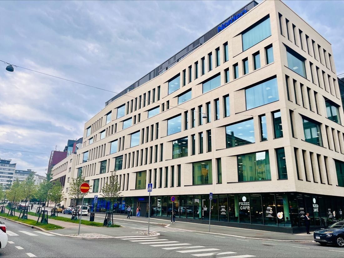 Nordea: Pale brick office building with a café on the ground floor at a street crossing