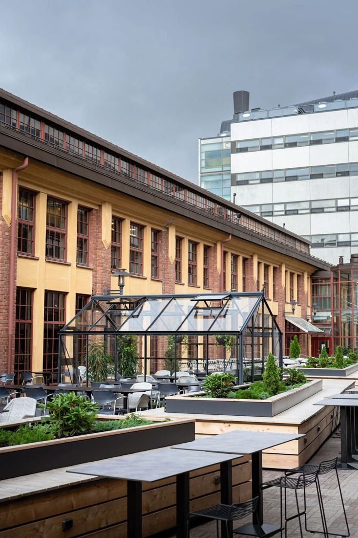 Nordea: Roof terrace with planters, standing tables and a small glasshouse beside a brick building