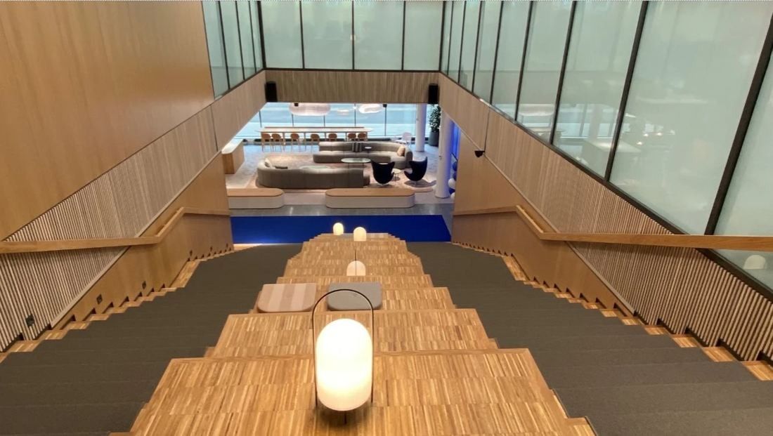 Nordea: Wide wooden staircase with seating steps and a lamp leading down to a lounge