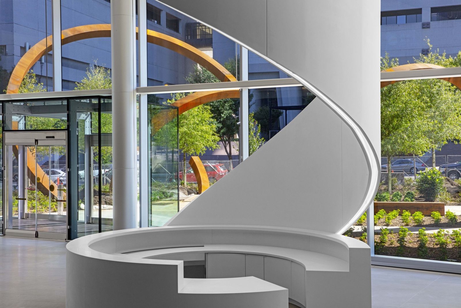 A white spiral stair rising beside the glass lobby