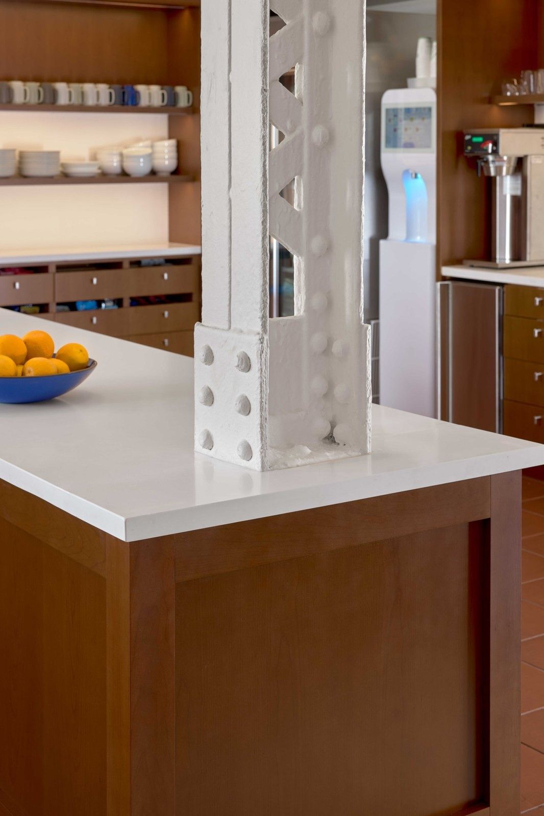 Notion: Close view of a riveted white steel column rising through a white stone counter