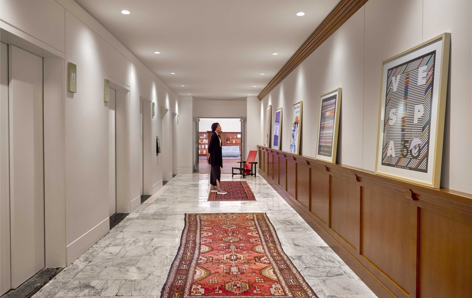 Notion: Marble-floored corridor with elevators, wood wainscoting, framed posters and Persian runners