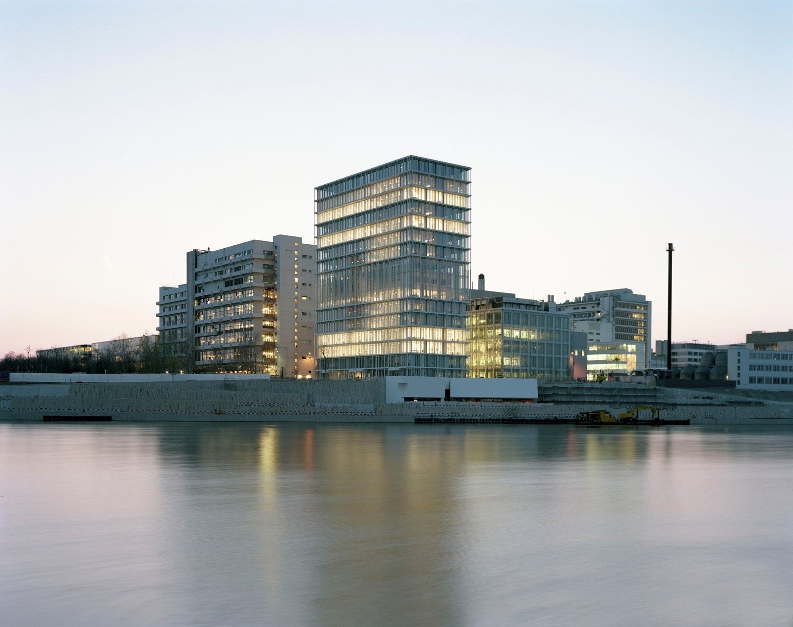 Glass office building lit at dusk on the Rhine