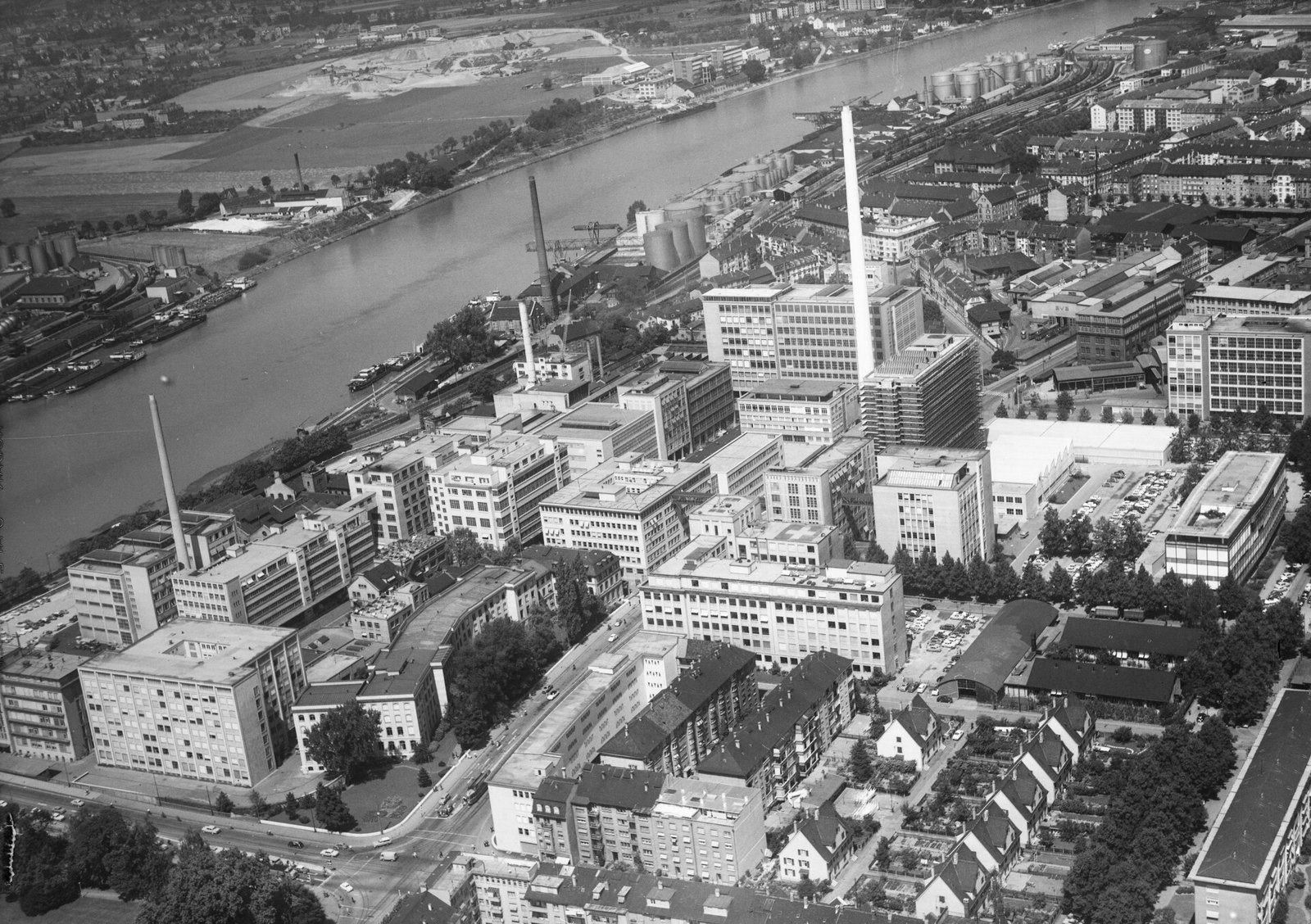 Black-and-white aerial view of a chemical works with a tall chimney by the Rhine