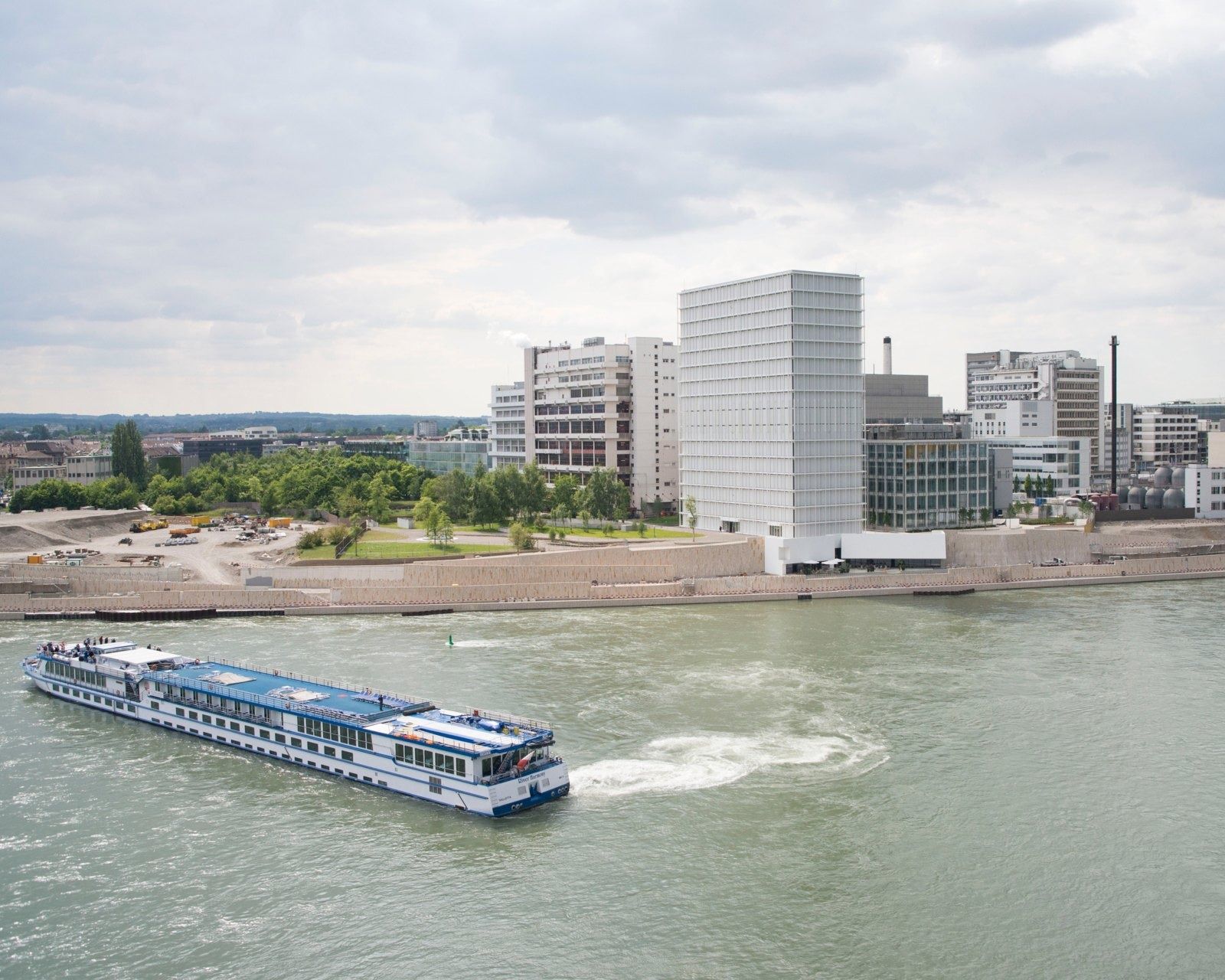 Novartis: Office tower beside the river with a passing cruise boat