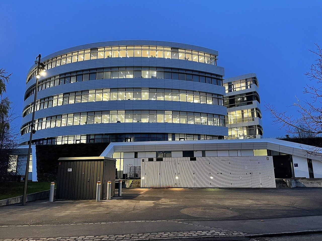 Curved glass office building lit at dusk