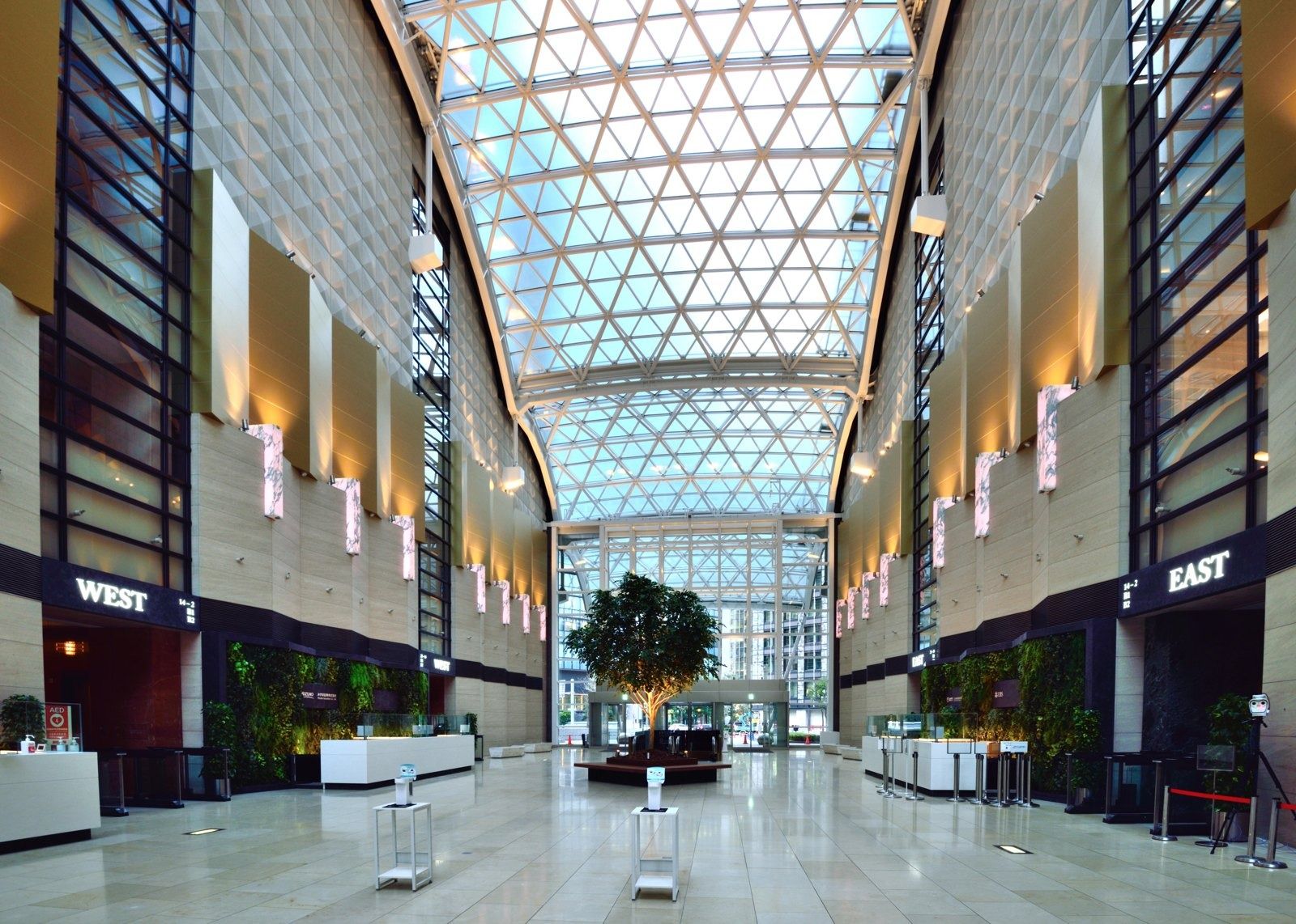 NTT: Tall glass-roofed atrium lined with stone walls