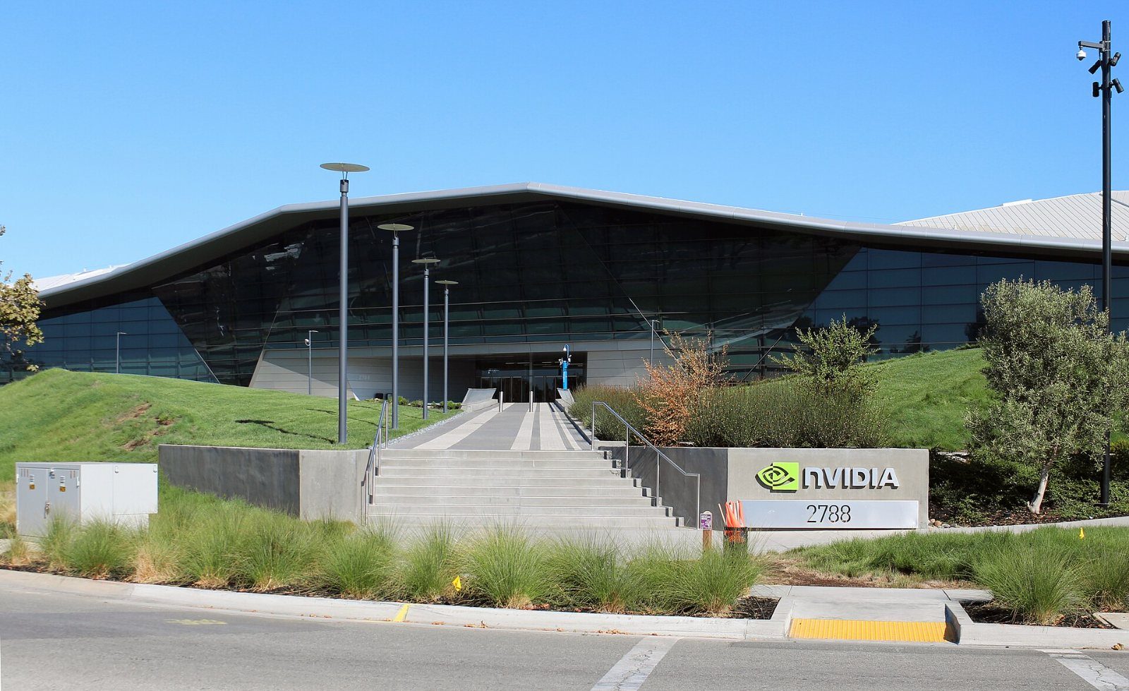 Low building with angled roof behind grass and steps