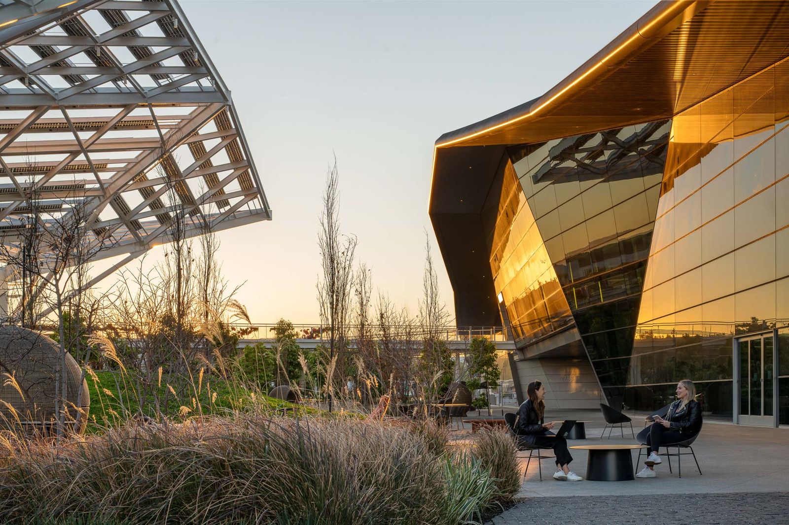 Outdoor seating at dusk next to the glass façade