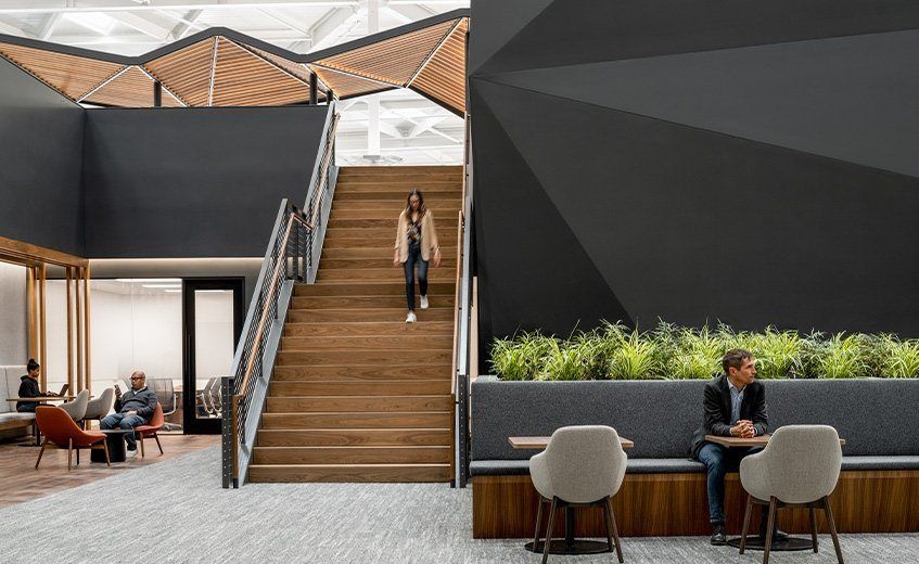 A wooden staircase between dark walls and planters
