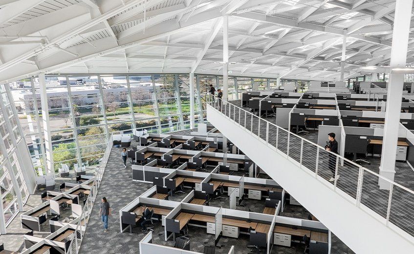 Rows of desks under Voyager's white roof with a long walkway above