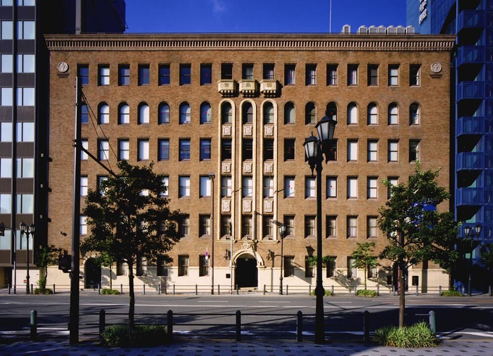 Brown-tiled historic office building with arched entrance and street lamps