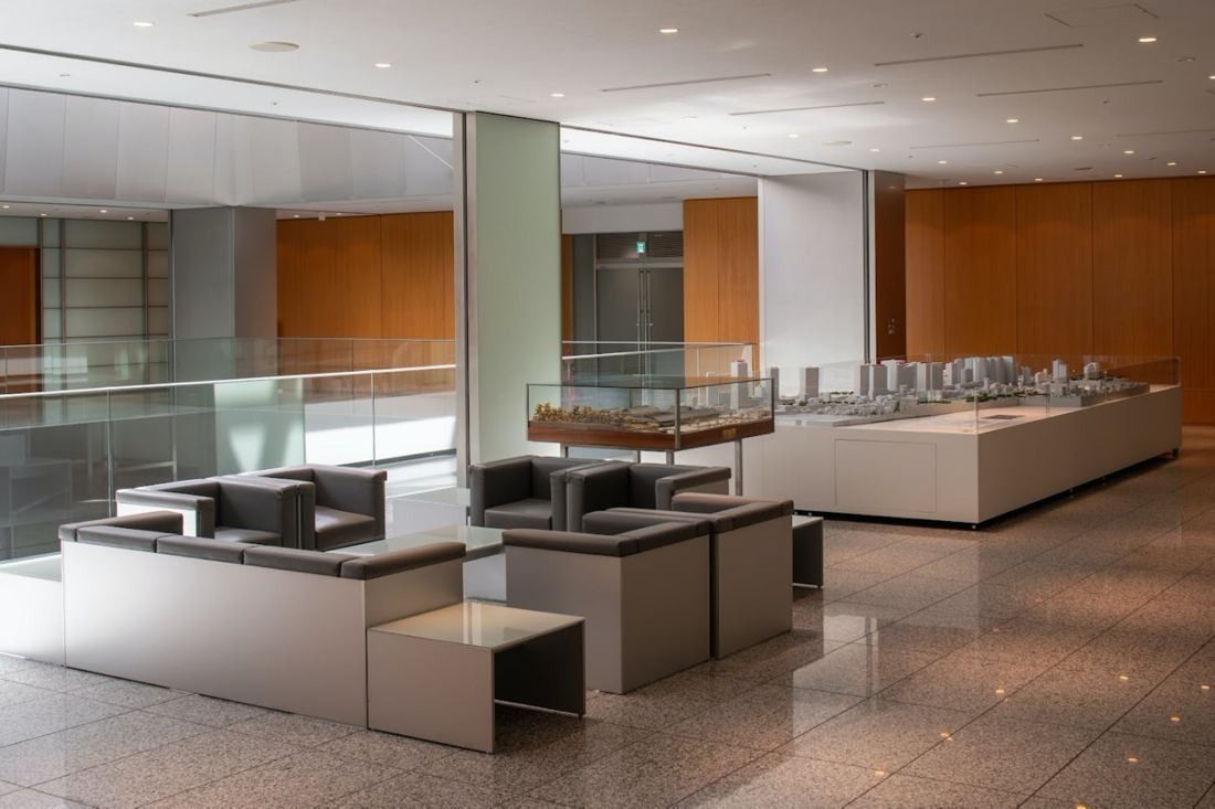 Obayashi: Display cases and low seating in a high-ceilinged space with a glass balustrade