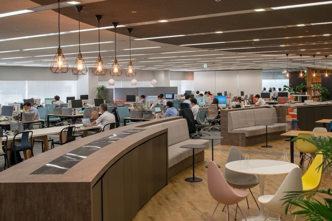 Obayashi: Office floor with pendant lamps, curved bench seating and pastel chairs