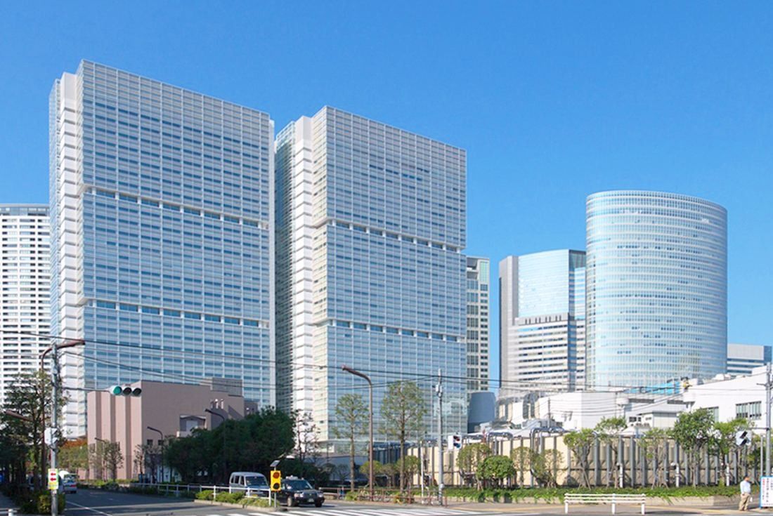Obayashi: Office towers seen across a street with trees in the foreground